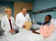 Imani Kutese (Florence Kasumba, rechts) bittet um eine Hüftoperation, die jedoch nicht zwingend notwendig ist. Aus diesem Grund bittet ihre behandelnde Ärztin Dr. Kathrin Globisch (Andrea Kathrin Loewig, links) Prof. Simoni (Dieter Bellmann) zu Rate.