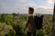 Guatemala - Albert Lin takes in the view from the top of Temple V at Tikal National Park in the Petén department of Guatemala. The main complex and its grand temples can be seen in the distance.