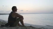 Darryl sits on a beach looking out at the ocean.