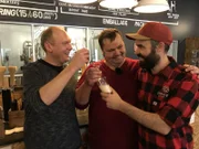 Von links: Hotelmanager Andreas Vespermann und Flotten-Küchenchef Fritz Pichler besuchen in Baie-Comeau, Kanada, eine Mikrobrauerei und treffen dort Brauer Pierre Antoine, der sie u.a. Krabbenbier probieren lässt.