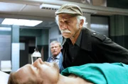 Dr. Jamm (Michael Kors, l.) ist ermordet worden. Edwin Bremer (Tilo Prückner, r.) mustert die Leiche, Kollege Günter Hoffmann (Wolfgang Winkler, im HG) hält sich im Hintergrund.