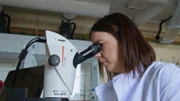 Eine Frau schaut durch ein Mikroskop