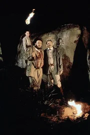 Der junge Jim (Darren P. Mercer) sowie die beiden Gelehrten Challenger (John Rhys-Davies, M.) und Summerlee (David Warner, li.) sind auf das Hochplateau der Flugsaurier zurückgekehrt. In den Höhlen der Eingeborenen machen sie eine aufregende Entdeckung.
