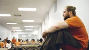 Zach Brill sitting on a bed at the Correctional Male Facility CDM