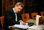Bürgermeister Schattenhofer (Werner Rom) nimmt den Lansinger Dichter-Wettbewerb sehr ernst und arbeitet heimlich an seinen Versen.