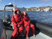 Reiseleiterin Maika Wuescher und Entertainment-Managerin Corina von Wedel-Gerlach, genannt Cori, sitzen auf einem Zodiac-Boot vor St. Pierre, wo sie eine Seehund-Kolonie besuchen.
