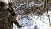 Charlie Wright (L) and Bob Wright (R) try and kill a lynx that is trapped in their trap.