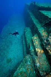 Ein Taucher untersucht die Sandsteinstruktur des unterseeischen Yonaguni-Denkmals. MYSTERIOUS ISLANDS nimmt die Zuschauer mit auf ein unvergessliches Abenteuer zur Erkundung der außergewöhnlichsten und rätselhaftesten Inseln unseres Planeten.