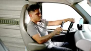 Ein Mann schaut während des Autofahrens auf sein Mobiltelefon