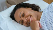 Close up of Vee C smiling as she lies on clinic bed during surgery