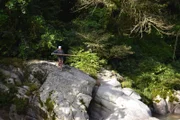 Cody Lundin with holding log above river.