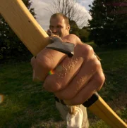 Monty aiming long bow at camera