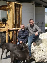 Lucas Congdon and Robert Krolikiewicz pose with Robert's dogs at his shop.