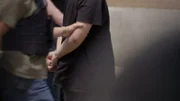 Zwei HSI-Agenten führen einen mit Handschellen gefesselten Verdächtigen bei einer Verhaftung wegen einer kontrollierten Lieferung ab. (National Geographic für Disney)
