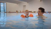 Marlis kann auf Grund ihres Kleinwuchses nicht schwimmen, umso wichtiger ist es, dass Maya früh schwimmen lernt. Schwimmkurs ist Papa-Sache.