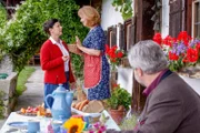 Hilde Stadler (Isabel Mergl, l.) bietet Marie (Karin Thaler, M.) an, noch mehr Marmelade aus den Johannisbeeren zu machen, was Kommissar Stadler (Dieter Fischer, r.) skeptisch verfolgt.
