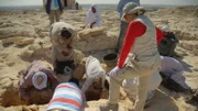 Das Ausgrabungsteam bürstet vorsichtig Sand von einem Grab in der Ausgrabungsstätte Taposiris Magna von Kathleen in Alexandria, Ägypten. Archäologen erforschen Leben und Tod in Ägyptens verlorener Megastadt Alexandria und entdecken den Zusammenstoß zweier Supermächte der antiken Welt.