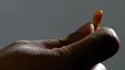 A hand holding a pill.