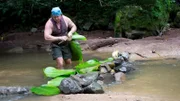 Cody Lundin with holding log above river.
