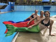 Reiseleiter Moritz und Entertainment-Managerin Corina machen in Montreal, Kanada, einen Meerjungfrauen-Schwimmkurs und posieren mit Marielle, ihrer Schwimmlehrerin vor Ort.
