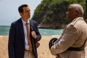 Detective Neville Parker (Ralf Little, l.) erfährt vom Polizeichef Selwyn Patterson (Don Warrington, r.) interessante Details über den Strand, die möglicherweise im Zusammenhang mit dem Mordfall stehen.