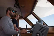 Darrell Miklos and Eric Schmitt steering the ship out to sea.