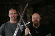 V.l.n.r.: Monty Halls und Stuart Prior halten ein Schwert und eine Poleaxt.