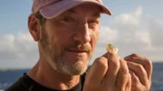 Darrell Miklos showing off recently discovered gold coins. (Close-up.)