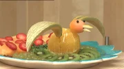 Aus viel leckerem Obst wird ein Orangenpfau mit Erdbeeraugen zubereitet.