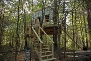 Workers build a cabin perched in the trees