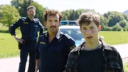 Quentin König (Thilo Fridolin Matthes, r.) berichtet den Polizisten Loisl (Sebastian Gerold, M.) und Charlie (Thomas Birnstiel, l.) aufgeregt von dem Jagdunfall seines Vaters.