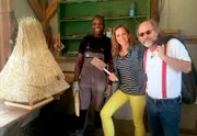 Moderatorin Tamina Kallert und Guide Klaus-Peter Wolf (Buchautor), hier mit Mitarbeiter Marco Bamezon (l), besuchen eine Dachdeckerbetrieb für die typischen Reetdachhäuser in der Region. Mit dem Gerät in Tamina Kallerts Hand werden Reetdächer eingedeckt.