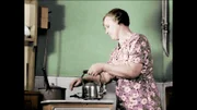 Frau in der Küche mit einem glänzenden Metallkessel auf ihrem Herd.