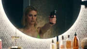 Franzi (Llewellyn Reichman) posiert mit Knarre vor dem Badezimmer Spiegel.