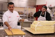 Buddy carves cake for Taco cake as Drew looks on.
