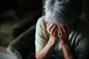 Eine Seniorin hält sich die Hände vors Gesicht.