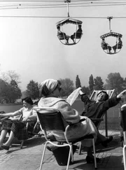 Die Gäste der Bundesgartenschau 1957 in Köln machen es sich auf bunten Stühlen gemütlich - über Ihnen die schweben die Kölner in der Seilbahn.