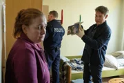 Kommissar Matti Wagner (Pierre Besson, r.) untersucht die Wohnung der besorgten Anja Vogel (Nadja Engel, l.), deren Sohn unmittelbar vor dem Mord am Tatort gesichtet wurde. Würde ihr eigener Sohn wirklich eine junge Frau erschießen? (Komparse im Bild)
