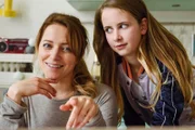 Anna (Diana Staehly, l.) und Steffi (Kyra Thoma) spielen mit den Vätern Monopoly.