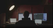 Ein Mann sitzt an einem Schreibtisch und arbeitet am Computer.
