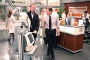 Wilson (Robert Sean Leonard, re.) fängt House (Hugh Laurie), der gerade den Laser in Foremans Büro bringen will, in der Lobby ab.