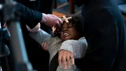 Father Miginot presses a cross to Latoya's forehead. Latoya looks possessed.