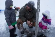 Kaleb stellt mit seinen beiden Kindern Gilbert und Elovie auf dem zugefrorenen Teich eine Biberfalle auf. (National Geographic/Kevin Nowicki)