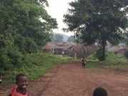 Shot of the road leading into a village while children smile at the camera.