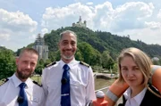 Kapitän Raul Kraaier und die Praktikanten Sebastian und Alexandra stehen vor der Marksburg in Braubach.
