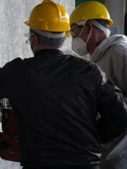 Zwei Männer beginnen mit dem Bohren einer Wand