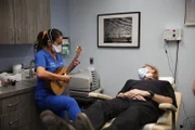 Dr. Lee plays her ukulele for Jerry Harrison post his cheek lipoma removal.