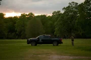 Warden Lauren Isles looking through binoculars next to her truck.