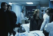 Mulder (David Duchovny, 2.v.l.) und Scully (Gillian Anderson, 2.v.r.) vermuten, dass die Bewohner, die ins Krankenhaus eingeliefert wurden, mit außerirdischen Lebensformen in Berührung kamen. Doch können sie davon auch Colonel Calvin Henderson (Marshall Bell, l.) und Dr. Oppenheim (William McDonald, r.) überzeugen?