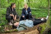 Moritz Brenner (Johannes Hendrik Langer, l.) und Ina Zimmermann (Melanie Marschke, r.) haben soeben die Leiche von Thilo Jedinger (Andreas Hammer, M.) im Wald entdeckt.